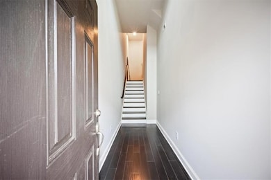 Hallway featuring dark wood finished floors, baseboards, and stairs