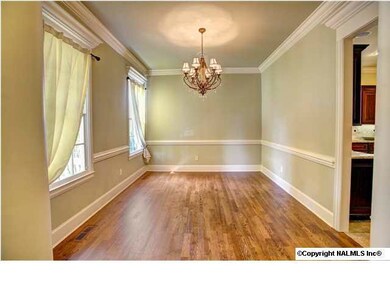 Spacious Dining Room with hardwood flooring, chair rail trim, crown molding and beautiful chandelier.