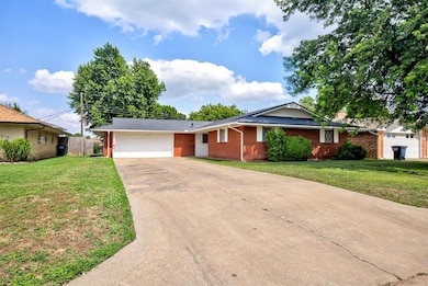 Single story home with driveway, brick siding, and a garage