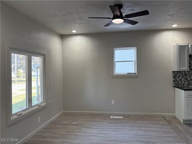 Unfurnished dining area with light wood-style flooring, ceiling fan, a textured wall, a textured ceiling, and recessed lighting