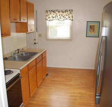 Kitchen: laminate flooring, large sink & access to the full basement or back patio/yard.