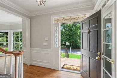Entryway with light wood-style floors, crown molding, and wainscoting