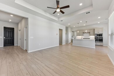 Unfurnished living room featuring a raised ceiling, recessed lighting, ceiling fan, and light wood-style flooring