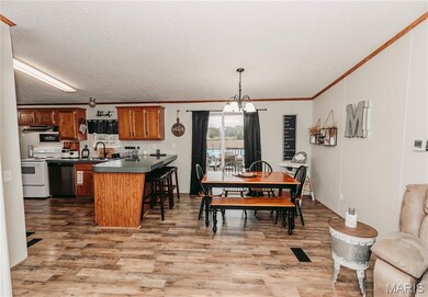 Kitchen with brown cabinets, dark countertops, electric stove, a chandelier, and a kitchen breakfast bar