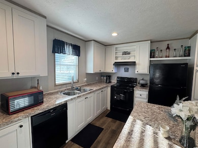 Kitchen featuring black appliances, open shelves, dark wood finished floors, white cabinets, and a textured ceiling