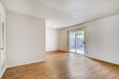 Empty room with a textured ceiling and light wood