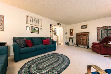 Living room featuring a textured ceiling, carpet flooring, and stairway