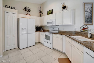 Kitchen featuring white cabinetry, sink, white app