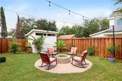 View of yard featuring a shed, a fire pit, an out