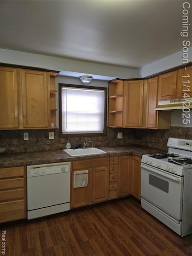 Kitchen with open shelves, white range, dark countertops, dishwashing machine, and dark wood-style flooring