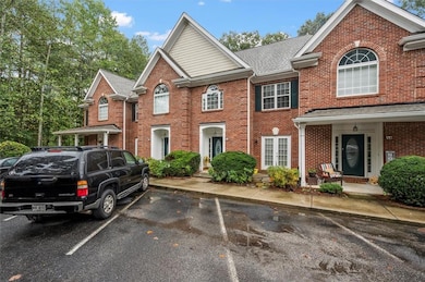 View of front of property with brick siding, uncovered parking, and a shingled roof