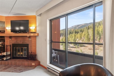 Living area with a brick fireplace, a baseboard heating unit, carpet, a textured ceiling, and wood walls