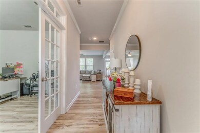 Hallway with french doors, ornamental molding, an office area, light wood-style flooring, and baseboards
