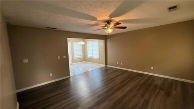 Spare room featuring ceiling fan, a chandelier, dark wood finished floors, and a textured ceiling