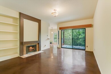 Unfurnished living room with built in shelves, a fireplace with flush hearth, and finished concrete flooring