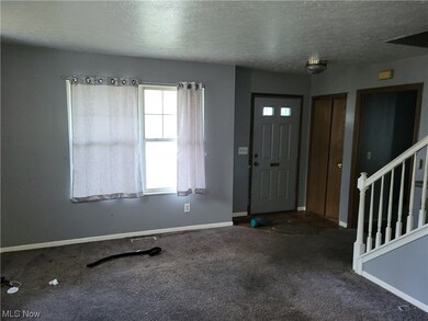 Foyer entrance featuring a textured ceiling and dark colored carpet