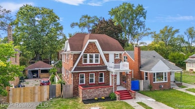 View of front of house featuring a chimney, brick siding, a gate, and a balcony