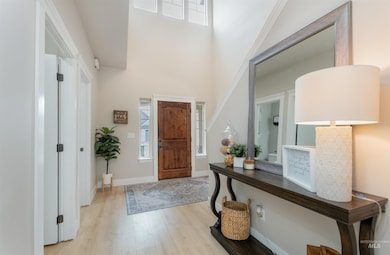 Foyer featuring light wood-style flooring and a towering ceiling