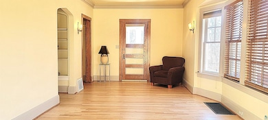 Sitting room featuring light wood finished floors, ornamental molding, a wealth of natural light, and visible vents