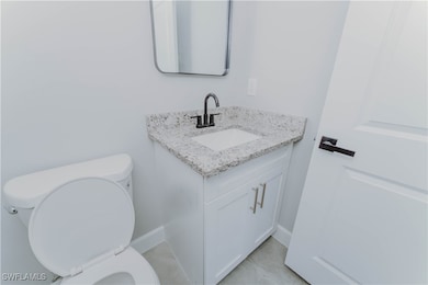 Bathroom featuring toilet, vanity, baseboards, and
