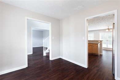 Empty room featuring a textured ceiling, dark wood-style floors, stairs, and a chandelier