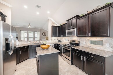 Fantastic island kitchen features beautiful granite countertops, tile backsplash, stainless steel appliances, gas range, under cabinet lighting and large breakfast bar.
