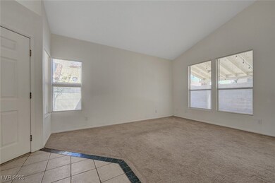 Empty room featuring light carpet, vaulted ceiling