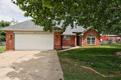 View of front of house featuring a garage, driveway, roof with shingles, and brick siding