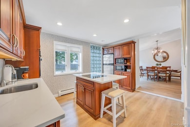Kitchen featuring brown cabinetry, light wood-type flooring, a kitchen breakfast bar, recessed lighting, and a kitchen island