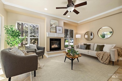 Living room featuring plenty of natural light, crown molding, a glass covered fireplace, recessed lighting, and a ceiling fan