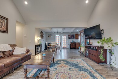 Living room has a vaulted ceiling and recessed lighting throughout