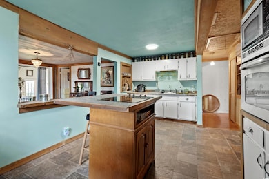 Kitchen with a kitchen island, stone tile flooring