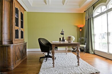 The formal living room features a coffered ceiling and arched windows and would also make an inviting music room or home office