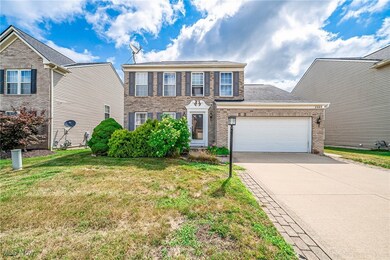 Colonial home featuring brick siding, concrete driveway, a front yard, and a garage