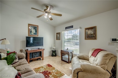Living room with vaulted ceiling, tile patterned flooring, and a ceiling fan