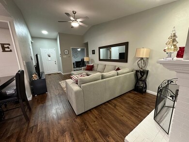 Living room with dark hardwood / wood-style flooring, ceiling fan, and vaulted ceiling