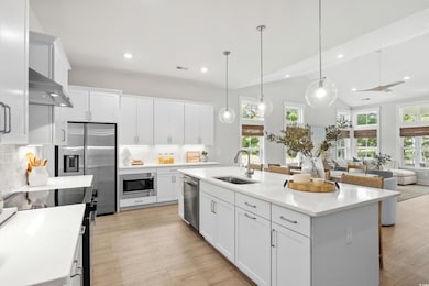 Kitchen featuring stainless steel appliances, white cabinetry, decorative light fixtures, tasteful backsplash, and recessed lighting