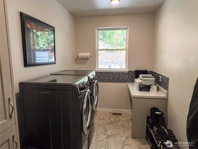 Good size utility room with front load appliances, storage cabinets and countertop that could double as a desk.