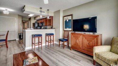 Living room featuring light wood-type flooring, a textured ceiling, and baseboards