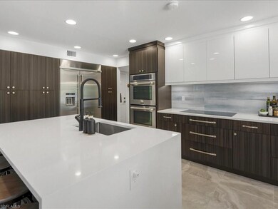 Kitchen with stainless steel appliances, modern cabinets, white cabinetry, dark brown cabinets, and recessed lighting