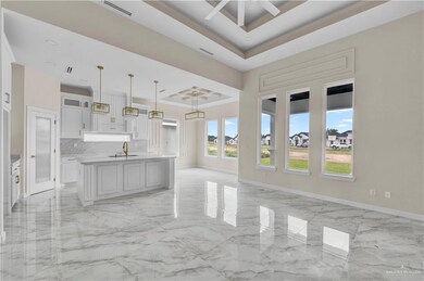 Kitchen with a raised ceiling, light marble finish flooring, open floor plan, and light countertops