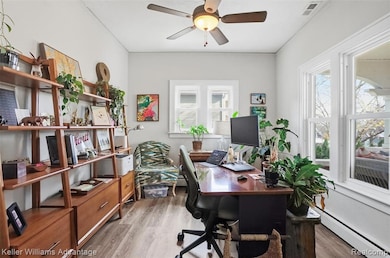 Office space with baseboard heating, light wood finished floors, healthy amount of natural light, and a ceiling fan