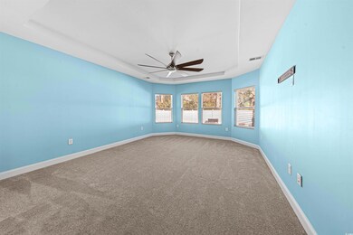 Carpeted spare room with ceiling fan and a tray ce