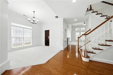 Foyer entrance with arched walkways, a chandelier, stairway, wood finished floors, and recessed lighting