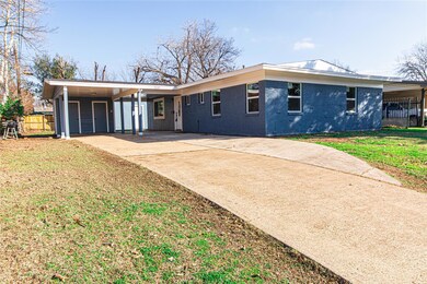 Back of property featuring a carport and a lawn