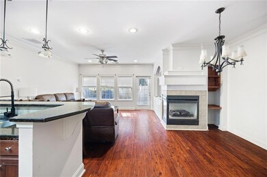 Living room with crown molding, dark wood finished floors, a tile fireplace, a ceiling fan, and recessed lighting