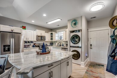 Kitchen featuring stainless steel appliances, light stone countertops, light wood finished floors, a kitchen bar, and tasteful backsplash