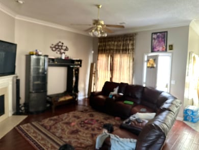Living room featuring ceiling fan, crown molding, 