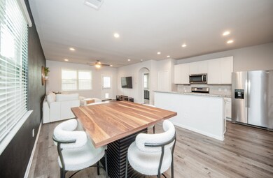 Modern open-plan kitchen and living space with stainless steel appliances, ample natural light, and stylish wood flooring. Perfect for entertaining and comfortable living.