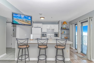Kitchen featuring white appliances, light countertops, white cabinetry, a breakfast bar, and light tile patterned flooring